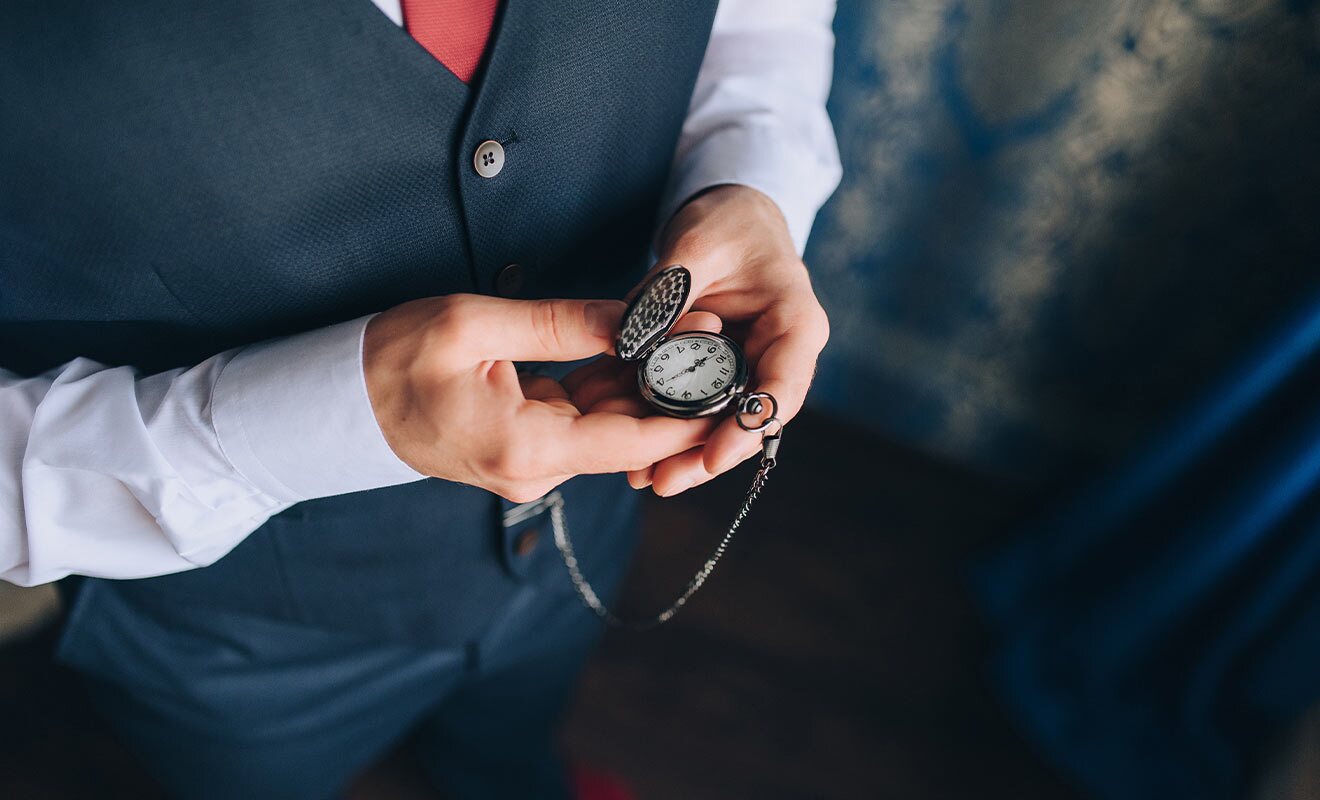 man wearing a vest holding a pocket watch