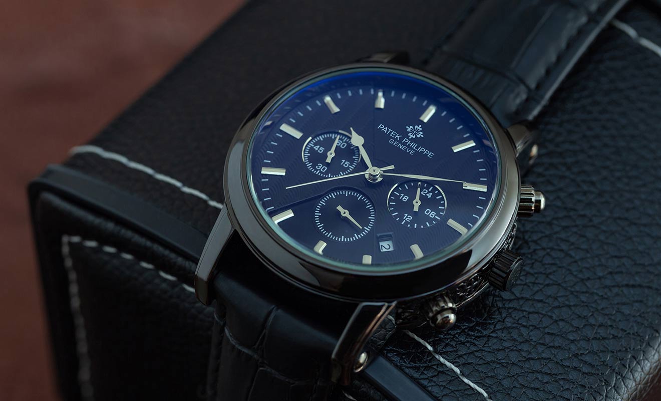 patek philippe watch with blue face laid on a black leather box