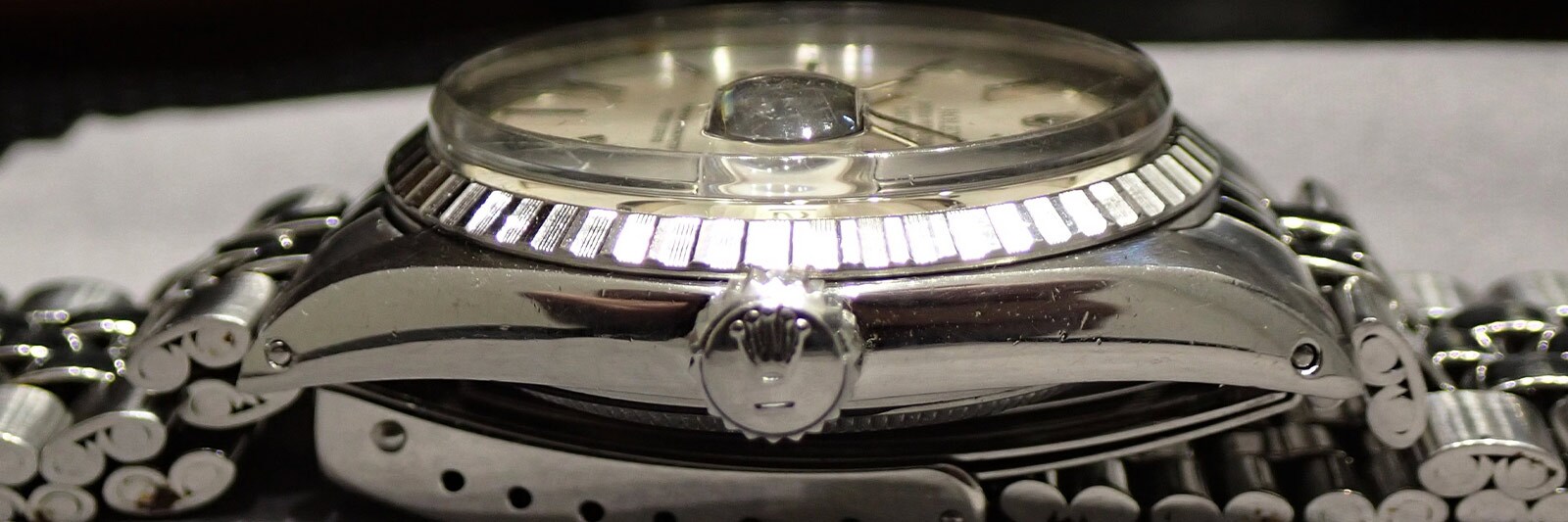 Close-up side view of a vintage Rolex watch case showing the crown, bezel, and crystal