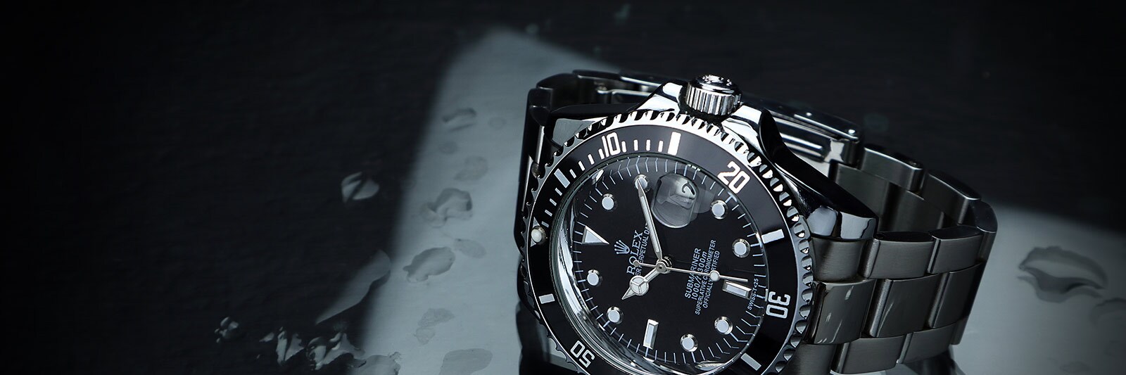 wet stainless steel rolex watch on a dark surface