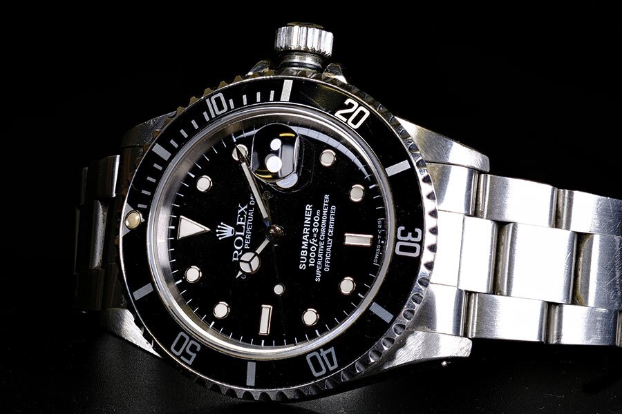 Black Rolex Submariner with oyster steel band on black background