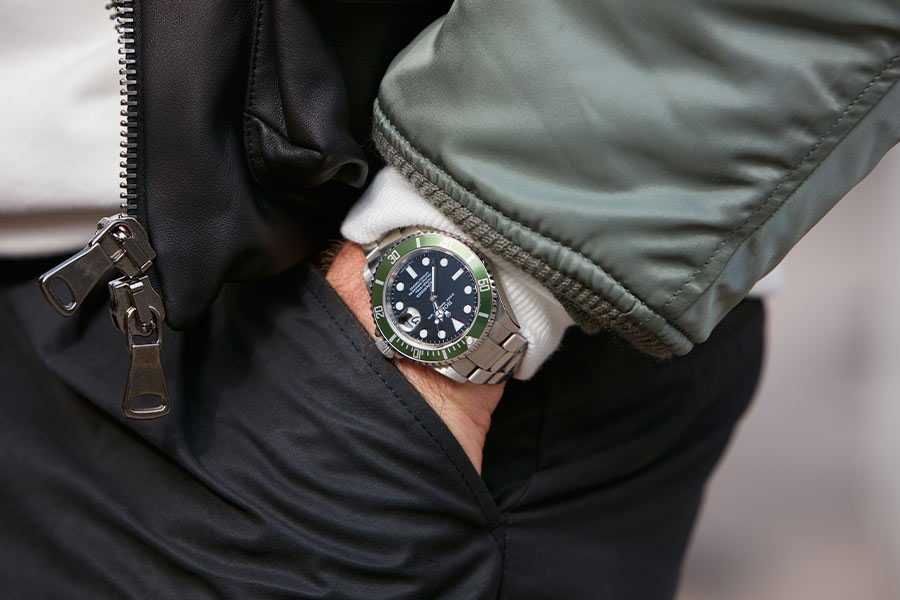 man wearing a green rolex submariner with a green jacket and dark pants