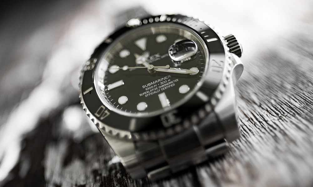 Black Rolex watch on a gray wooden surface during watch authentication services